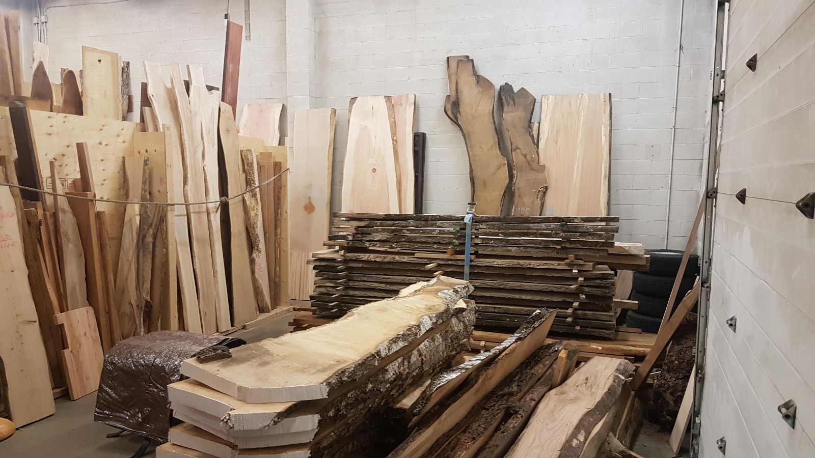 The workshop — live-edge hardwood slabs sorted and stored upright against the wall, ready for milling