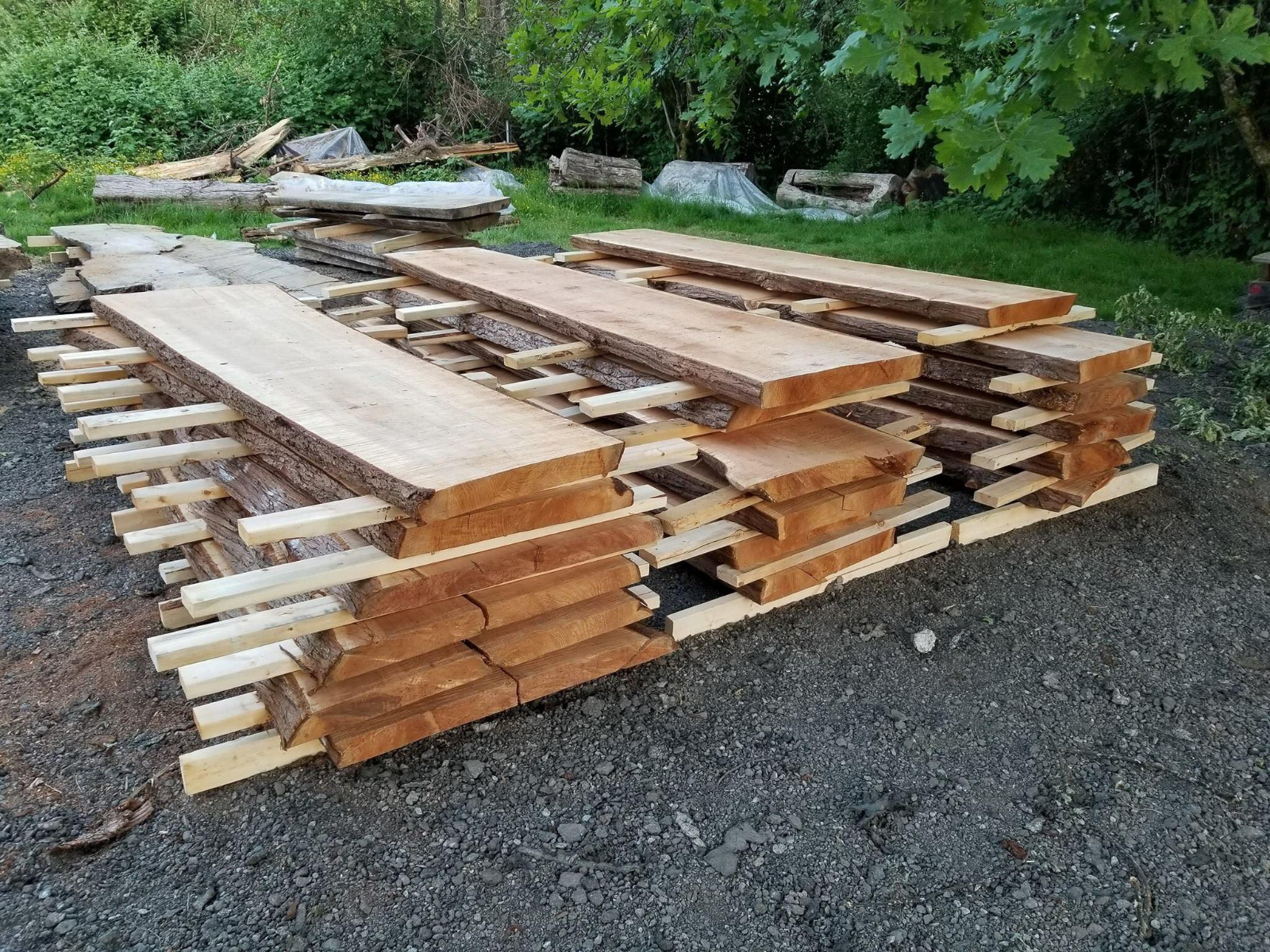 Locally-sourced hardwood stickered and stacked outdoors to air-dry before milling