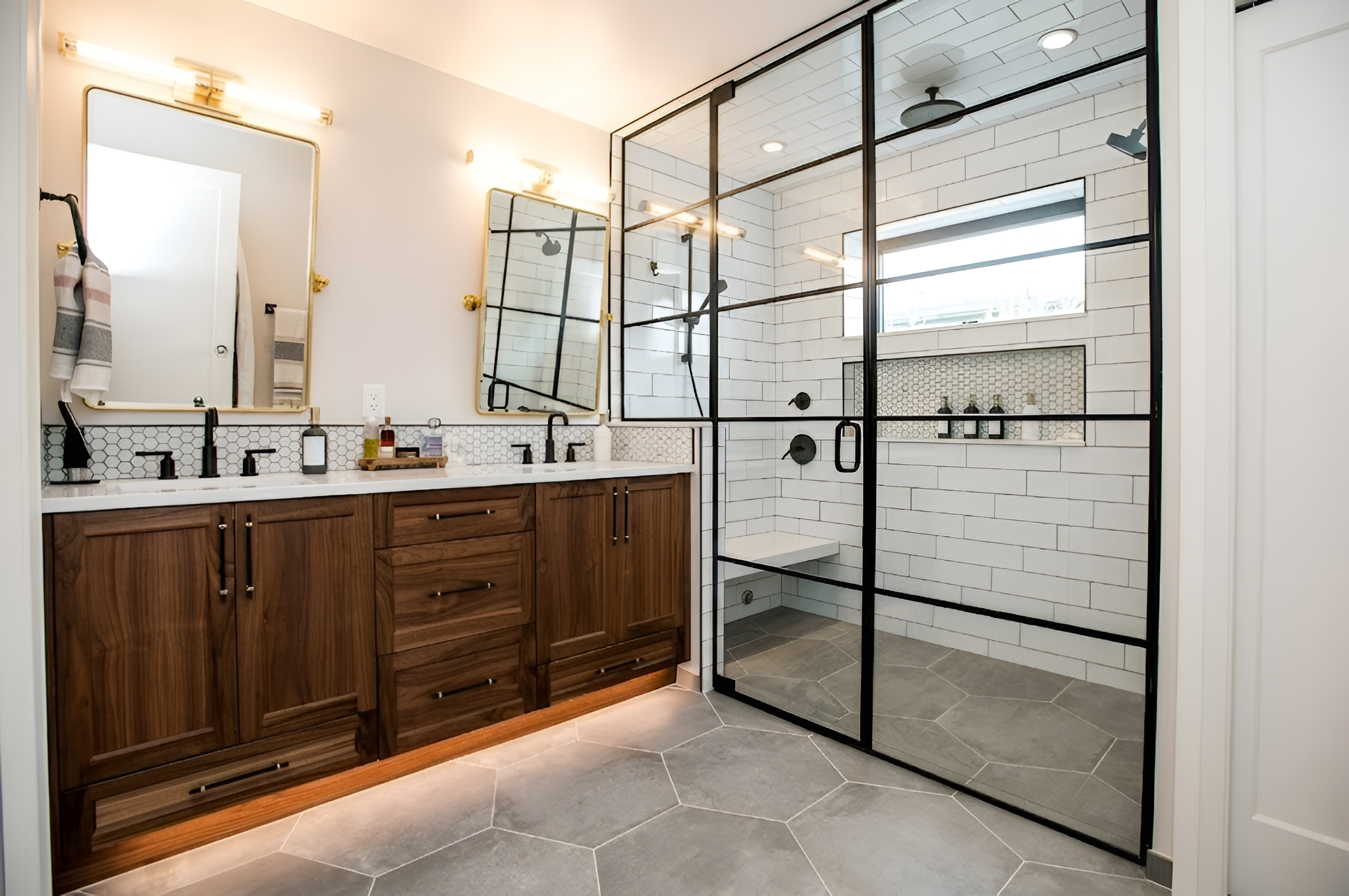 Primary bathroom with walnut double vanity, black-framed glass shower and hexagonal slate floor