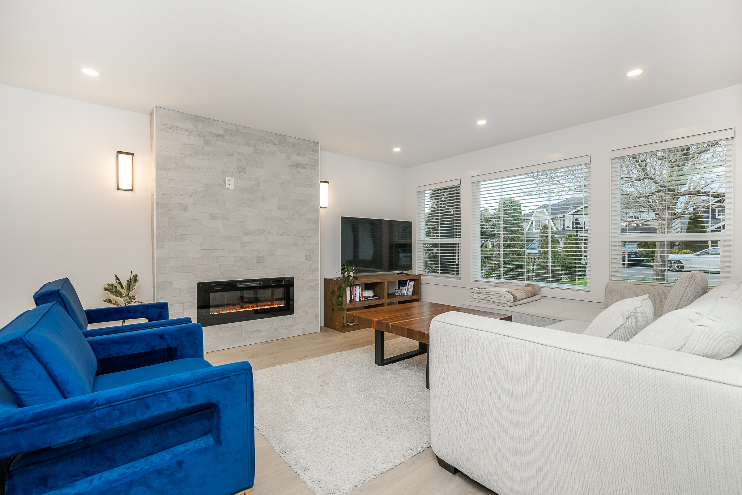Living room with linear fireplace, stone surround and blue velvet armchairs