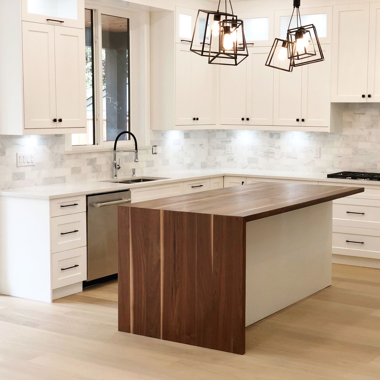 White shaker kitchen with walnut island, marble backsplash and black cage pendants