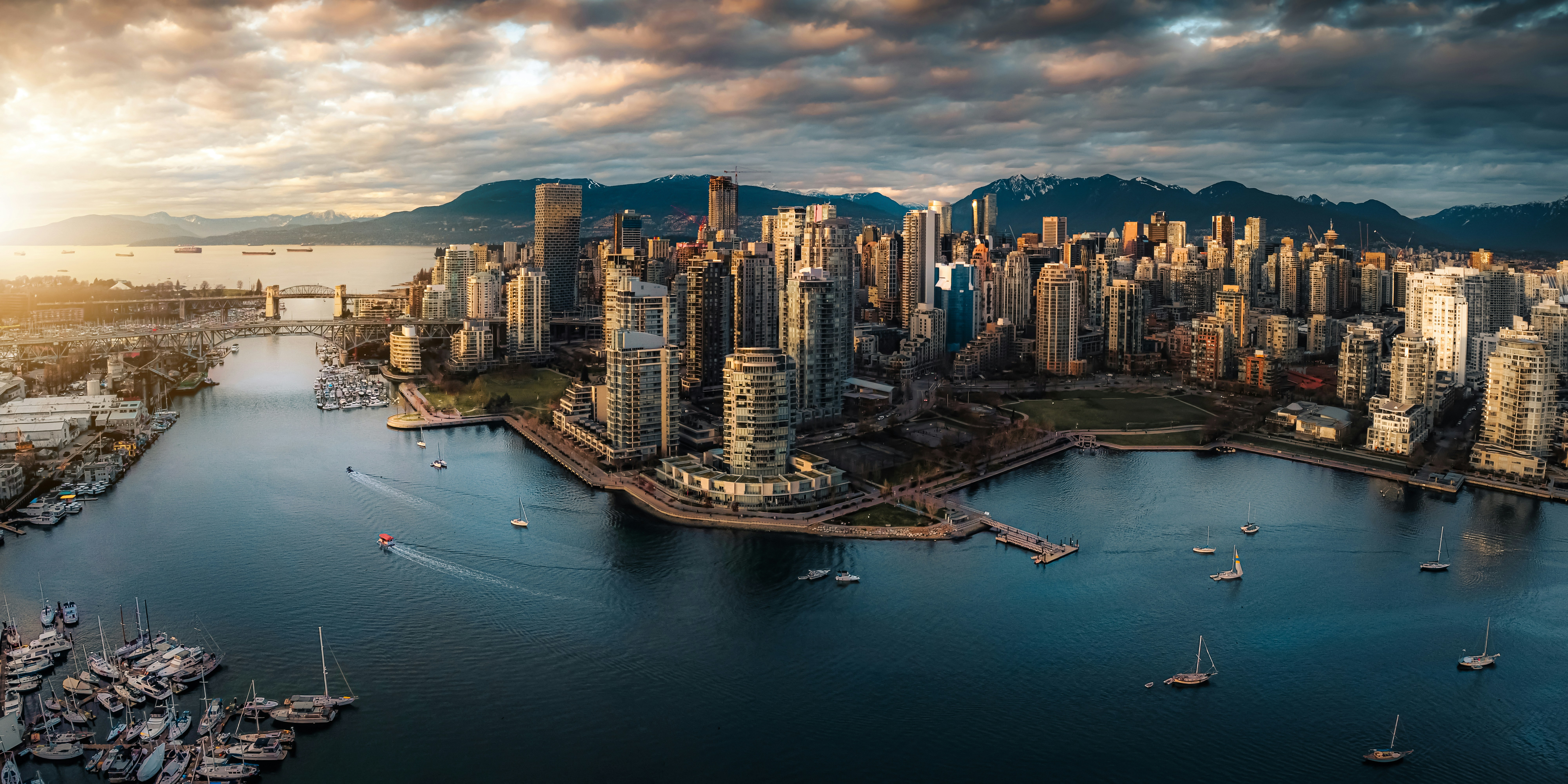 Aerial panorama of downtown Vancouver at sunset — False Creek marina and the city skyline against the snow-capped North Shore mountains