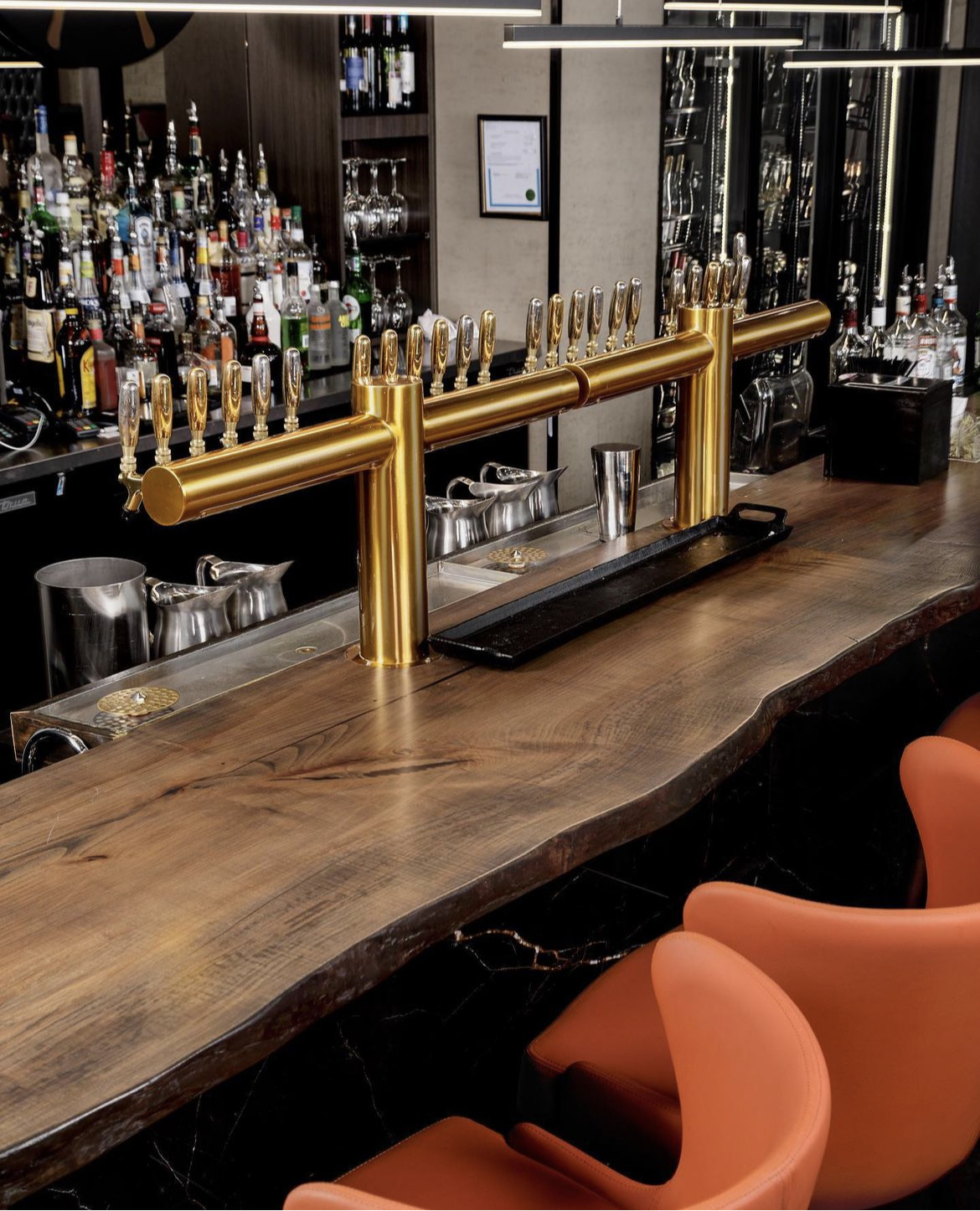 Custom built-in wet bar with brass beer taps and live-edge walnut counter