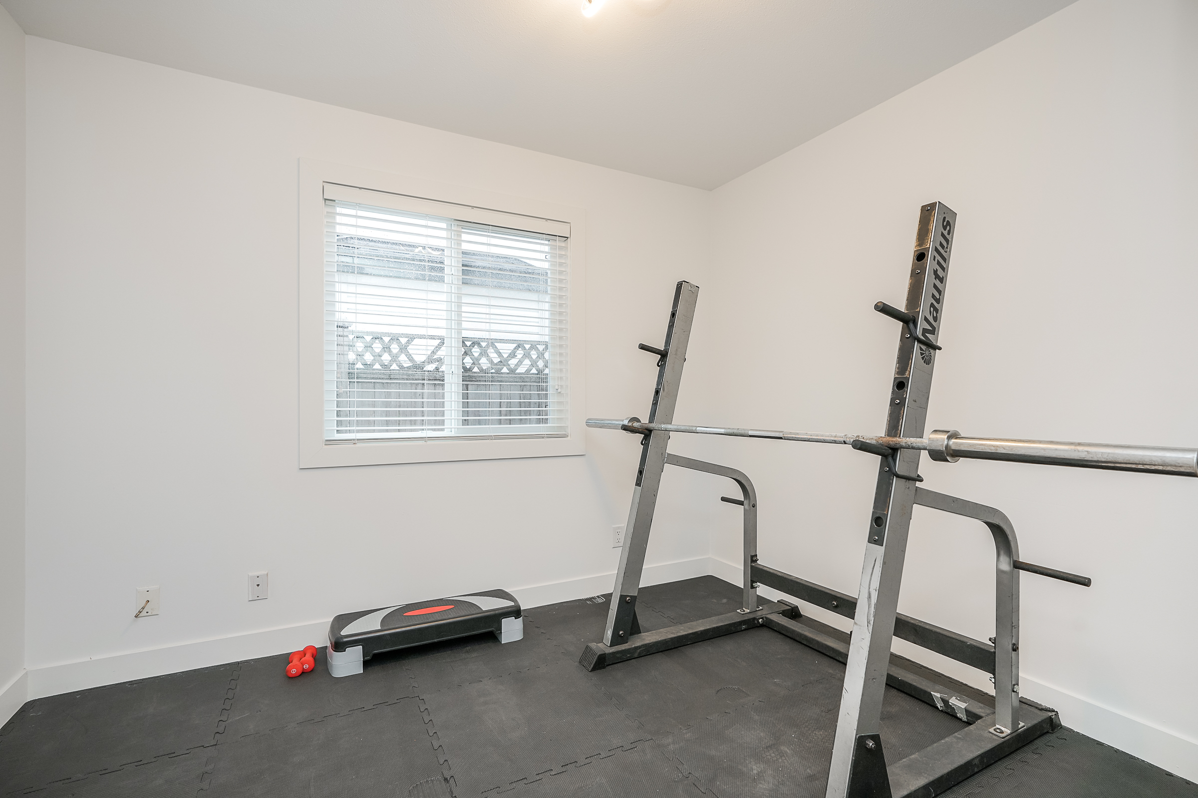 Home gym with squat rack, rubber mat flooring and natural light
