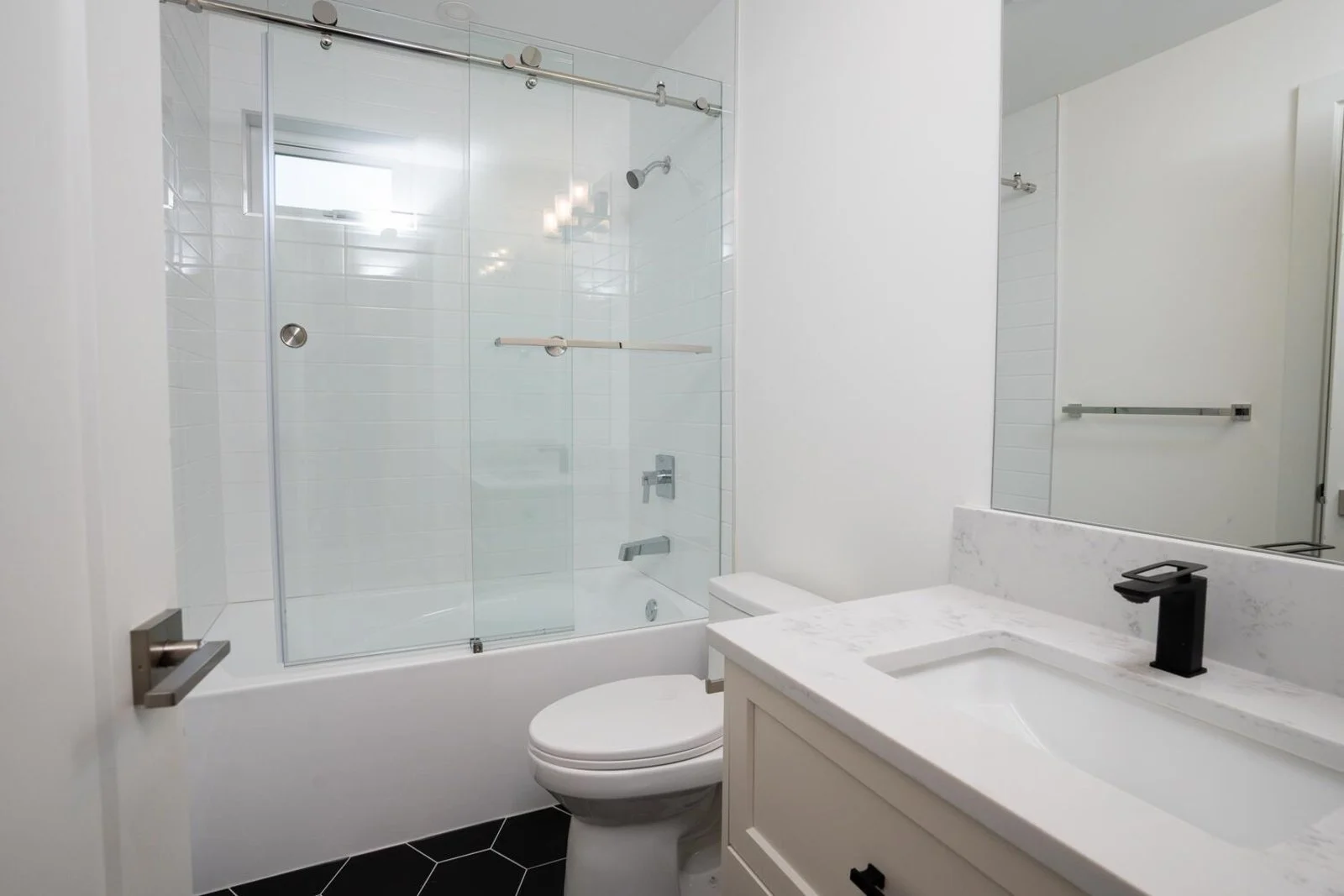 Suite bathroom with subway tile, glass tub enclosure and quartz vanity