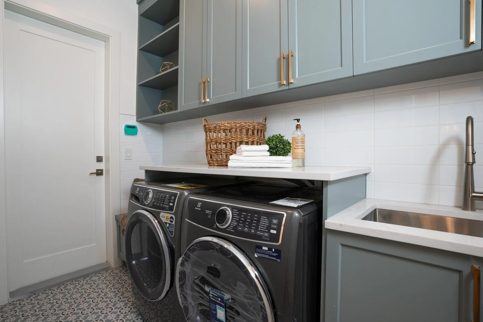 Laundry room with sage cabinetry, brass pulls and patterned cement tile floor