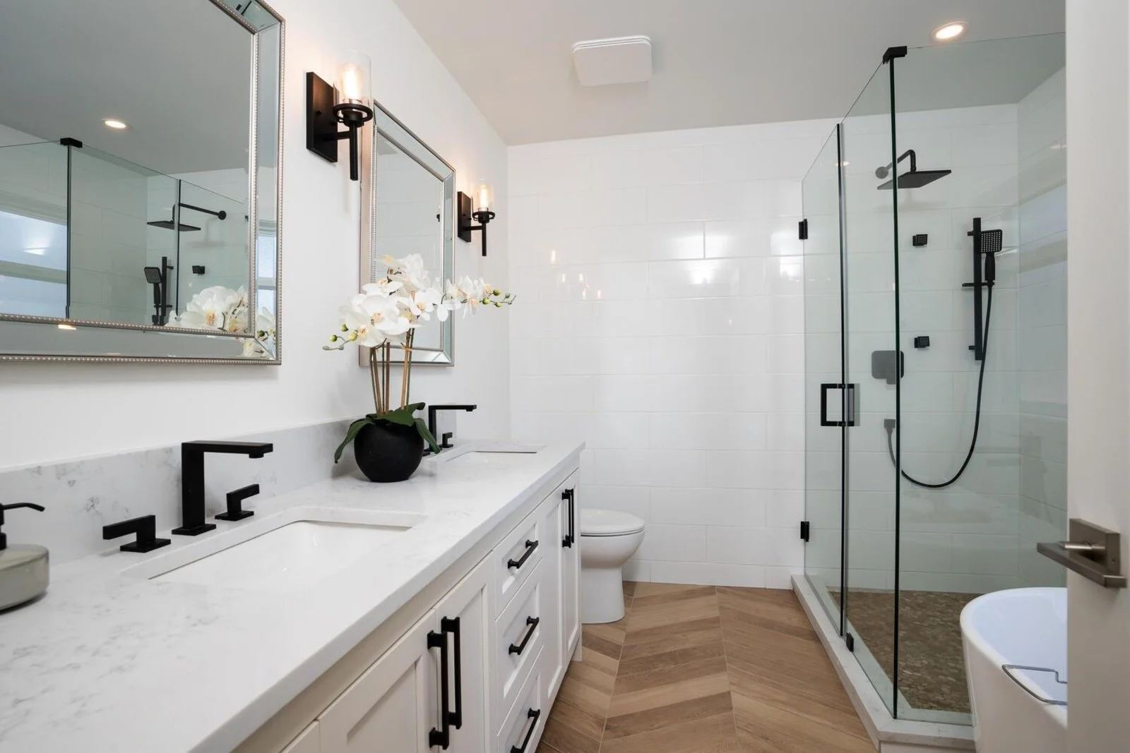 Primary ensuite double vanity with marble counters and matte black sconces