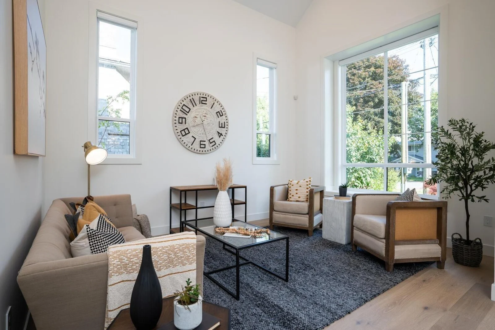 Bright living room with vaulted ceilings, large windows and warm neutral furnishings